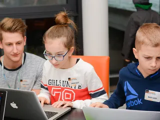 Mentor mit Schülern und Laptops